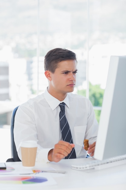 Giovane uomo d&#39;affari che aggrotta le sopracciglia mentre guardando il computer