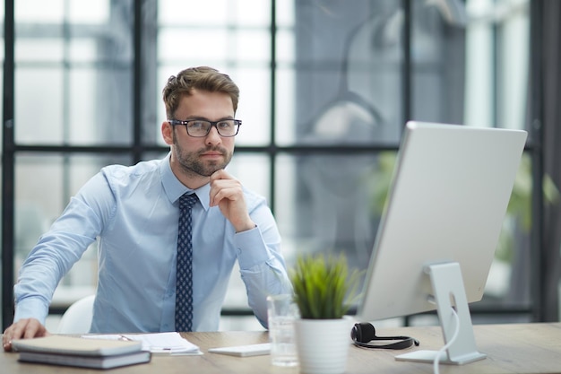 Giovane uomo d'affari che lavora al moderno ufficio di vetro