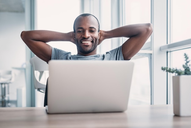 Giovane uomo d'affari che lavora al suo computer portatile in un ufficio spazioso e luminoso.