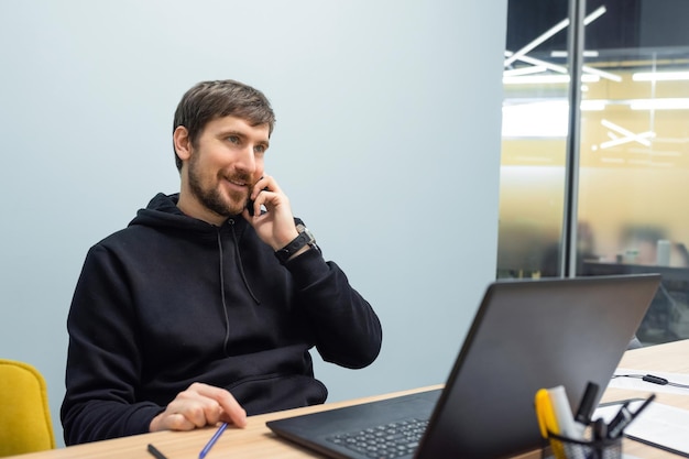 Giovane uomo d'affari che lavora in ufficio parlando al telefono Concetto di business