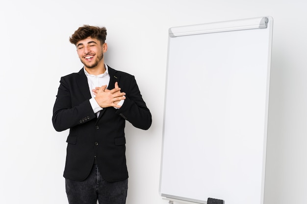 Giovane uomo d'affari che prepara uomo arabo che ride tenendo le mani sul cuore, concetto di felicità.