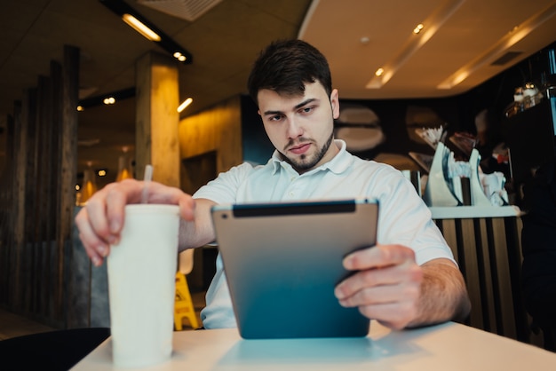 Giovane uomo d'affari che utilizza compressa in un caffè