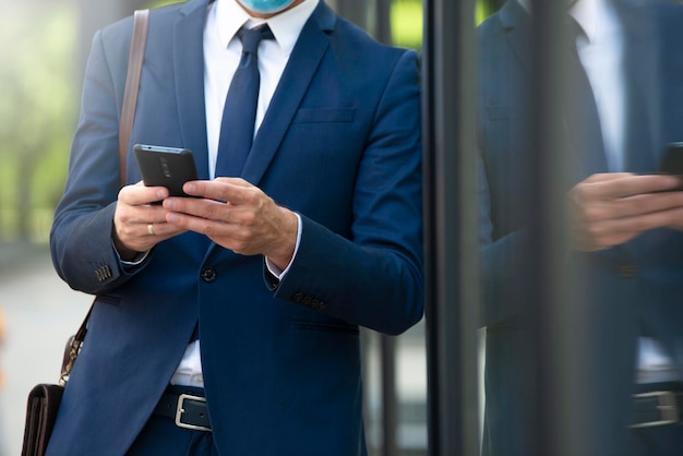 Giovane uomo d'affari con le marche utilizzando il primo piano all'aperto del telefono