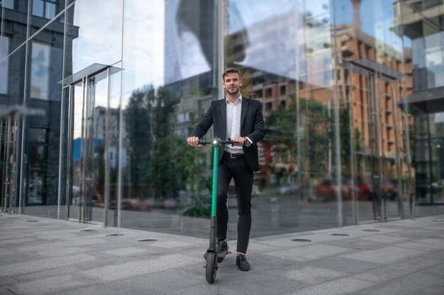 Giovane uomo d'affari con lo scooter in strada