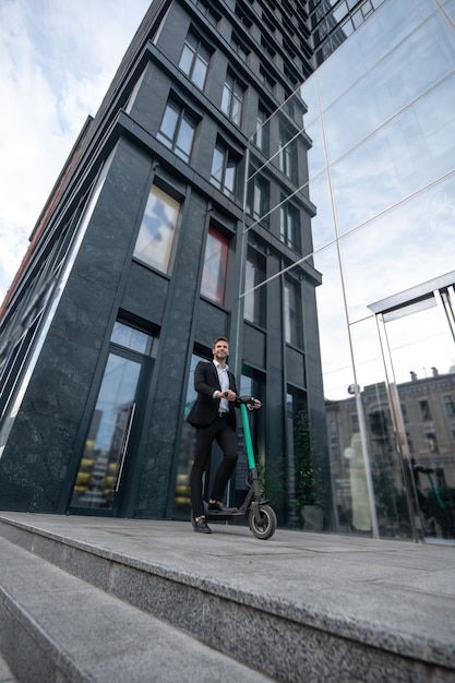 Giovane uomo d'affari con lo scooter in strada