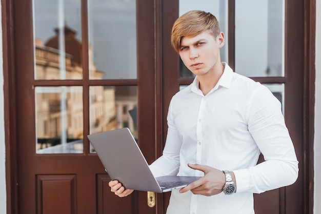 Giovane uomo d'affari di successo in stile business con laptop in mano