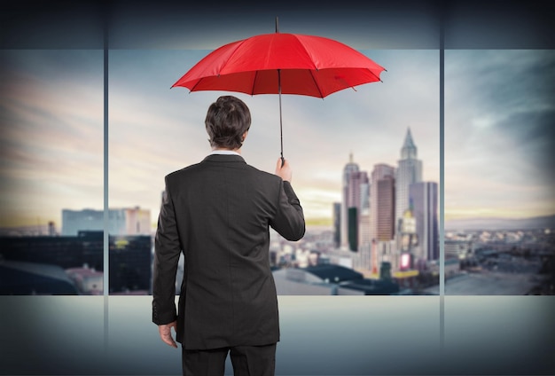 Giovane uomo d'affari in abito grigio con ombrello rosso