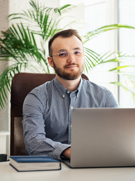 Giovane uomo d'affari in camicia che lavora al suo computer portatile in un ufficio