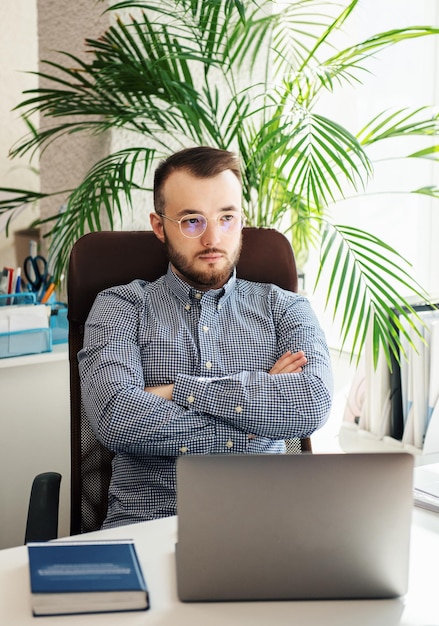 Giovane uomo d'affari in camicia che lavora al suo computer portatile in un ufficio