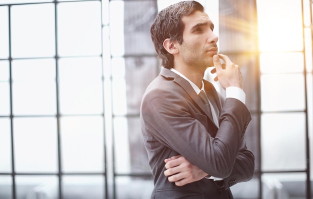 Giovane uomo d'affari in vista di profilo con la mano sul mento in ufficio