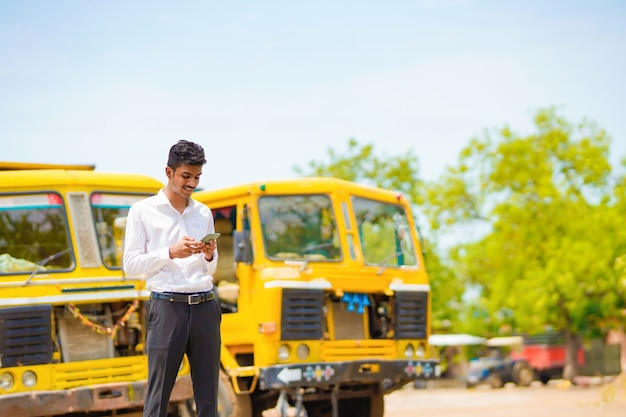 Giovane uomo d'affari indiano con il suo camion o camion in avanti.