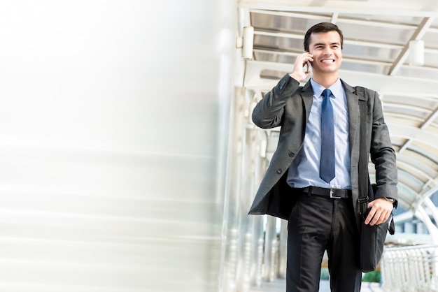 Giovane uomo d&#39;affari ispanico bello che cammina e che invita telefono cellulare