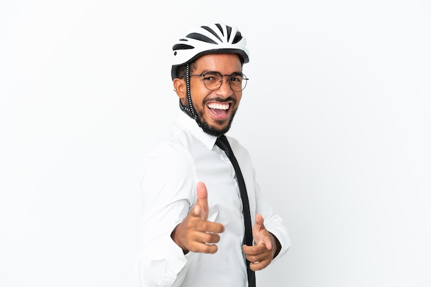 Giovane uomo d'affari latino che tiene un casco da bici isolato su sfondo bianco rivolto verso la parte anteriore e sorridente