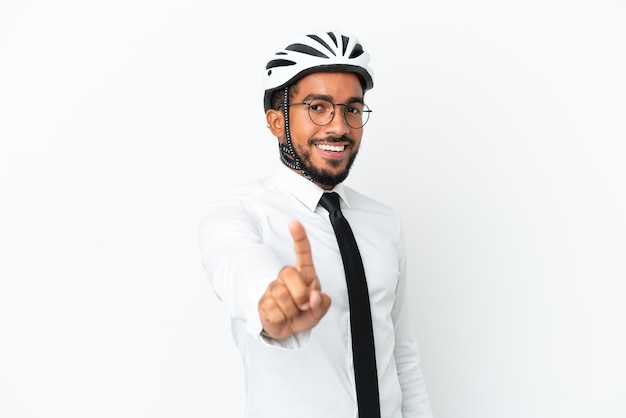 Giovane uomo d'affari latino in possesso di un casco da bici isolato su sfondo bianco che mostra e alzando un dito