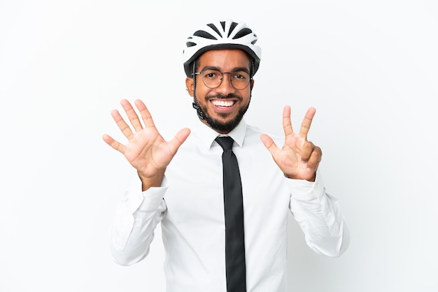 Giovane uomo d'affari latino in possesso di un casco da bici isolato su sfondo bianco contando otto con le dita