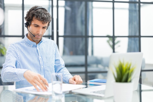 Giovane uomo d'affari moderno che analizza i dati utilizzando il computer mentre si lavora in ufficio