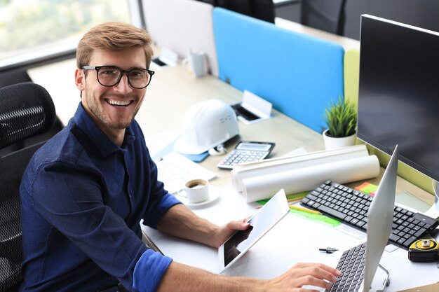 Giovane uomo d'affari moderno che analizza i dati utilizzando il computer portatile mentre si lavora in ufficio.