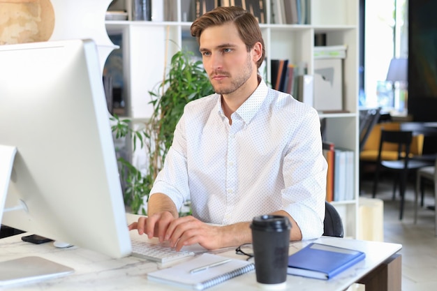 Giovane uomo d'affari moderno che lavora utilizzando il computer mentre è seduto in ufficio.