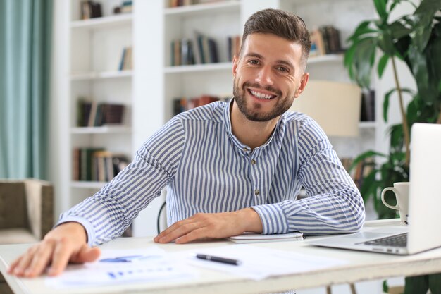 Giovane uomo d'affari moderno che lavora utilizzando il computer portatile mentre è seduto in ufficio.