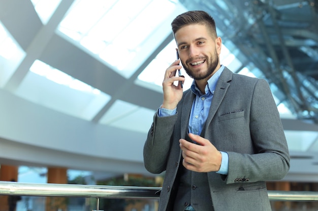 Giovane uomo d'affari sorridente che chiama telefono in ufficio.