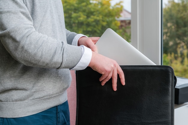 Giovane uomo d'affari tirando fuori un computer portatile da una custodia in pelle in ufficio.