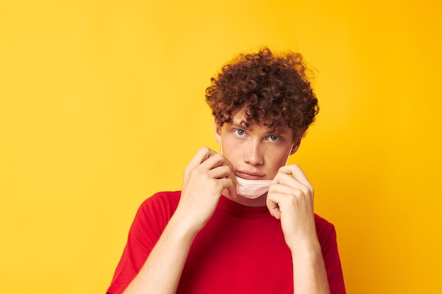 Giovane uomo dai capelli ricci con uno stile di vita di protezione della maschera medica maglietta rossa inalterato