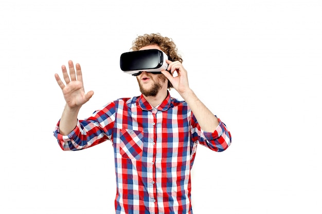 Giovane uomo dai capelli ricci in camicia a quadri utilizzando un auricolare VR e exp