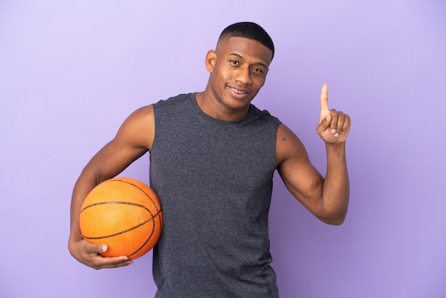 Giovane uomo del giocatore di basket latino isolato sulla parete viola rivolta verso l'alto una grande idea