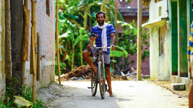 Giovane uomo del villaggio con l'immagine del ragazzo del lavoro dell'agricoltore della bicicletta