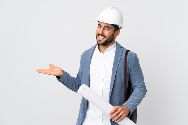 Giovane uomo dell'architetto con il casco e giudicare i modelli isolati sulla parete bianca che presenta un'idea mentre guardando sorridere verso