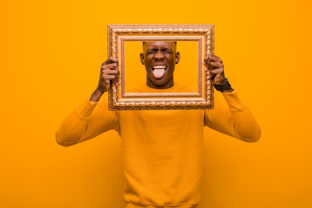 Giovane uomo di colore afroamericano contro la parete arancio con una struttura barrocco