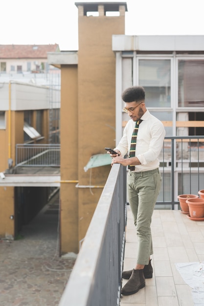 Giovane uomo di colore all&#39;aperto utilizzando smart phone