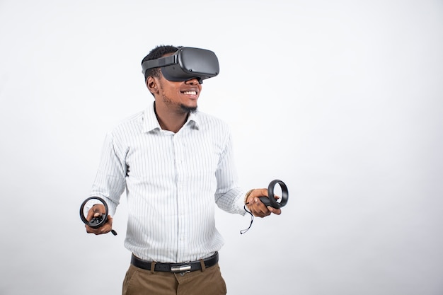 Giovane uomo di colore che sorride mentre utilizza un auricolare vr e controller