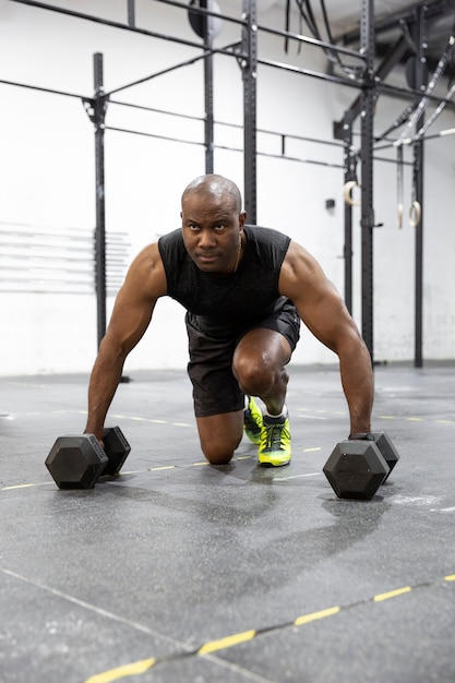 Giovane uomo di colore forte che fa allenamento fitness in palestra. Spazio per il testo.