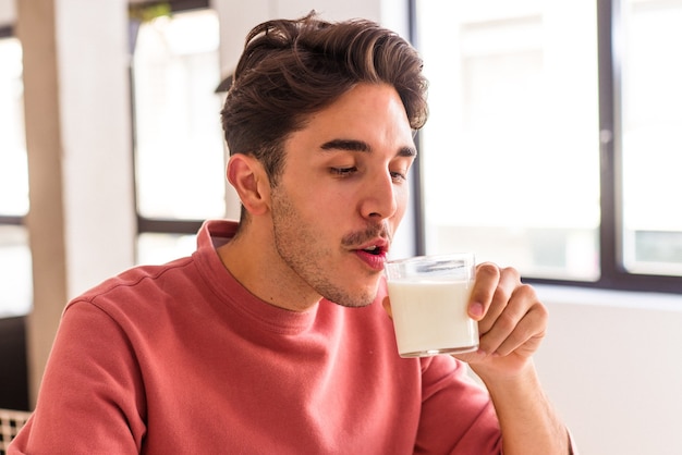 Giovane uomo di razza mista che beve latte a colazione