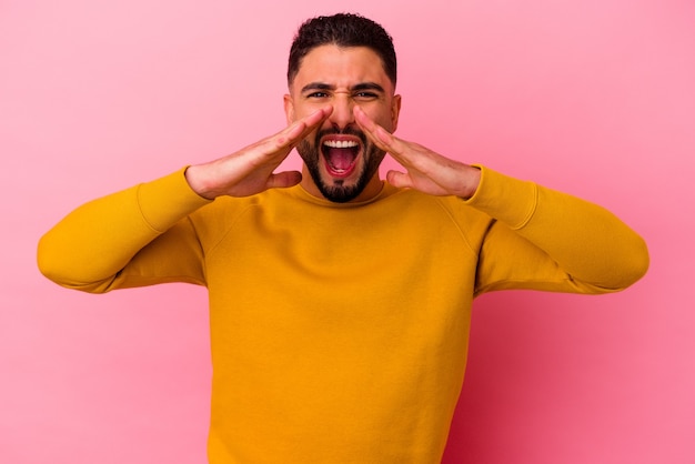 Giovane uomo di razza mista isolato su rosa gridando eccitato di fronte.