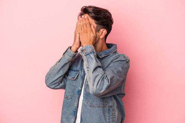 Giovane uomo di razza mista isolato su sfondo bianco paura che copre gli occhi con le mani.