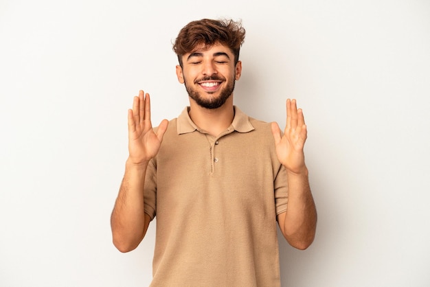 Giovane uomo di razza mista isolato su sfondo grigio gioioso ridendo molto. Concetto di felicità.