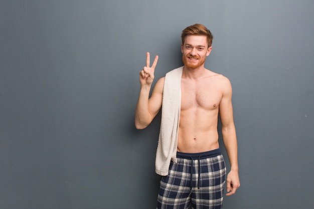 Giovane uomo di redhead che tiene un tovagliolo che mostra numero due