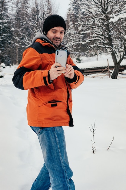 Giovane uomo di scattare una foto con lo smartphone sorridente giornata invernale neve collina alberi campagna