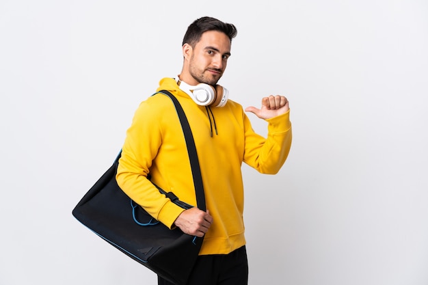 Giovane uomo di sport con borsa sportiva isolato sul muro bianco orgoglioso e soddisfatto di sé