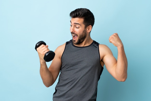 Giovane uomo di sport con la barba che fa sollevamento pesi che celebra una vittoria