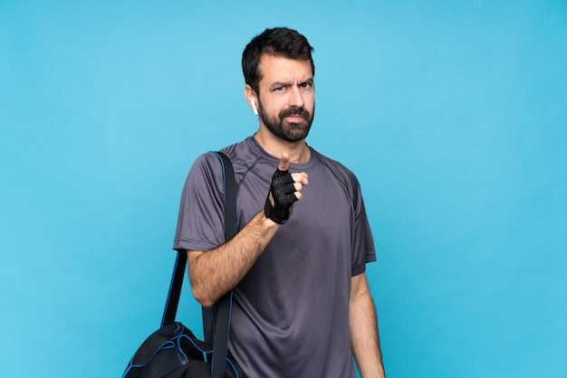 Giovane uomo di sport con la barba sopra isolato blu frustrato e che punta verso la parte anteriore