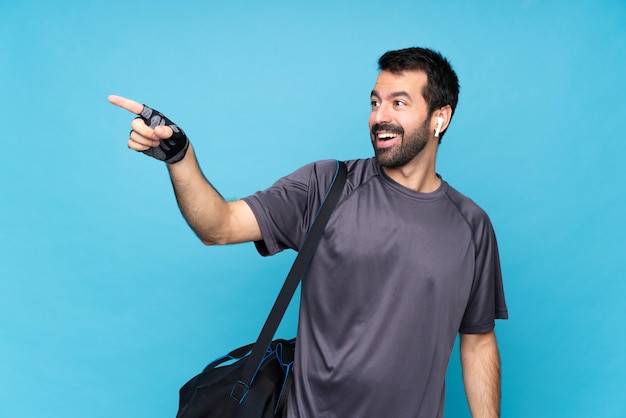 Giovane uomo di sport con la barba sopra la parete blu isolata che indica via