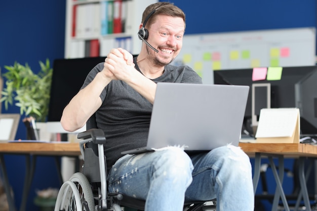 Giovane uomo disabile in cuffie che comunicano tramite laptop. Concetto di incontri online