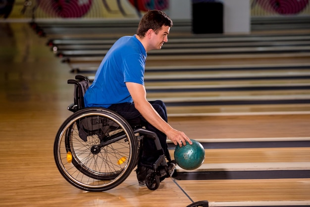 Giovane uomo disabile in sedia a rotelle giocando a bowling nel club