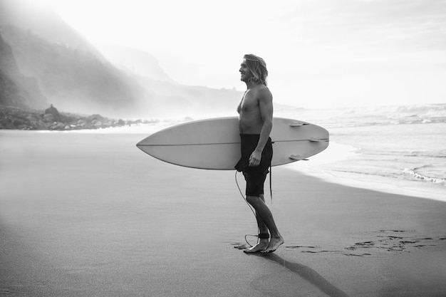 Giovane uomo divertirsi sulla spiaggia dopo la sessione di surf Concentrarsi sul viso Modifica in bianco e nero
