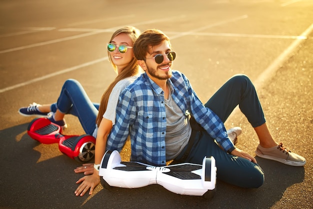 Giovane uomo e donna che cavalcano l'Hoverboard nel parco contengono tecnologie un nuovo movimento