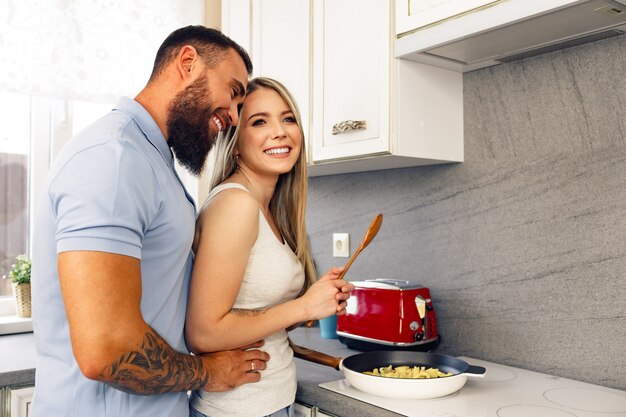 Giovane uomo e donna che cucinano cibo in cucina insieme coppia felice che prepara cibo