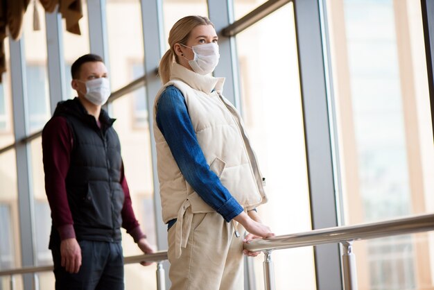 Giovane uomo e donna che indossa maschere mediche in una lounge dell'aeroporto